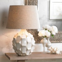 This classic midcentury modern table lamp features a handsome ceramic base with a dramatic design The resulting look is full and rich with a texture that is both eyecatching and stylishly sculpted Its topped with a linen drum shade that provides a natural