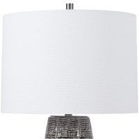 Classic and stylish on its own this table lamp showcases clean lines and creativity Resting atop round base it has vase shaped body with brick pattern which adds to the overall beauty The round shaped fabric shade allows the light to filter through and cr