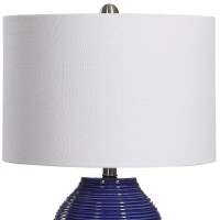 Classic and stylish on its own this table lamp showcases clean lines and creativity Crafted from ceramic it has jar shaped body with ribbed design which adds to the overall beauty The round shaped fabric shade allows the light to filter through and create