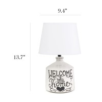 Check out this finelooking jugular shaped table lamp spruced with a bit of a rustic appeal A washed out and slightly unfinished ceramic base is decorated with a black written script and paired with a white linen fabric shade In todays world of interior de