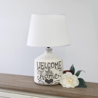 Check out this finelooking jugular shaped table lamp spruced with a bit of a rustic appeal A washed out and slightly unfinished ceramic base is decorated with a black written script and paired with a white linen fabric shade In todays world of interior de