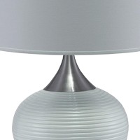 Style up your living space with a contemporary touch by bringing in this sophisticated table lamp Featuring a pot bellied ceramic body it showcases stylish horizontal textured details with metal accents It is incorporated with a fabric drum shade that use