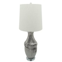 Crafted from durable ceramic this stylish table lamp adds a bright splash of confidence to your interior The urn shaped body with textured lines add an elegant and classic flair to the piece while the elongated round fabric shade with a finial on top give