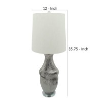 Crafted from durable ceramic this stylish table lamp adds a bright splash of confidence to your interior The urn shaped body with textured lines add an elegant and classic flair to the piece while the elongated round fabric shade with a finial on top give